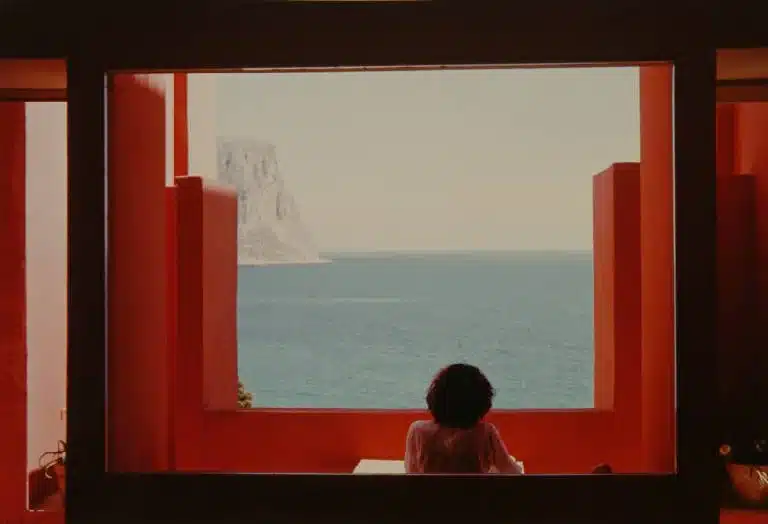 Lo scatto realizzato da Carla Cerati di fronte alla Muralla Roja, iconico complesso residenziale postmoderno a Calpe, in Spagna, famoso per il suo design labirintico ispirato alle kasbah, gli esterni dai vivaci colori rosso, rosa e blu e la piscina sul tetto.