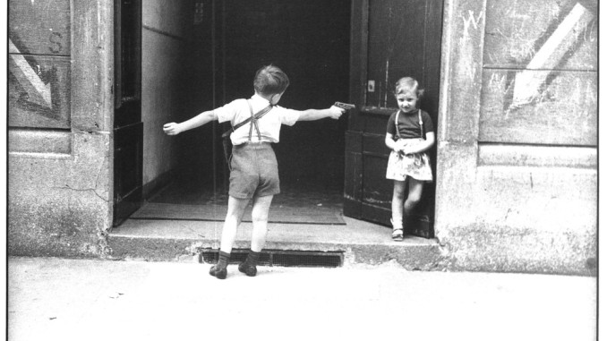 Un bambino e una bambina giocano davanti a un portone in zona Fiera. a Milano, a metà degli Anni Sessanta. Lo scatto è di Carla Cerati. 